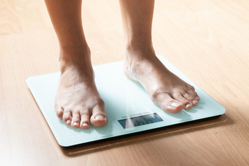The legs of a young woman on the scales. Weight check. The concept of losing weight.