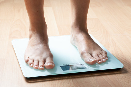 The legs of a young woman on the scales. Weight check. The concept of losing weight.