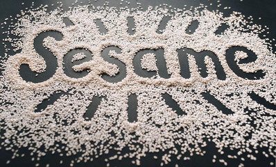 The funny big word Sesame is written among a multitude of grains on a black background. Symbol of healthy nutrition and vegetarianism.