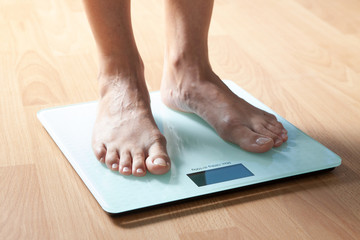 The legs of a young woman on the scales. Weight check. The concept of losing weight.