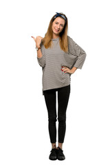Obraz premium A full-length shot of a Young woman with headscarf pointing to the side to present a product over isolated white background