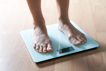 The legs of a young woman on the scales. Weight check. The concept of losing weight.