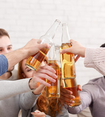 Friends clinking beer bottles, having home party