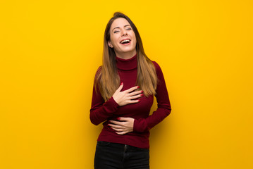 Obraz premium Woman with turtleneck over yellow wall smiling a lot