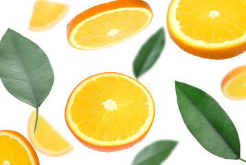 Flying juicy orange slices and citrus leaves on white background