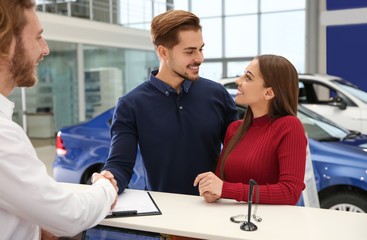 Car salesman and young couple in dealership