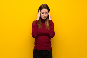 Fototapeta premium Woman with turtleneck over yellow wall with headache