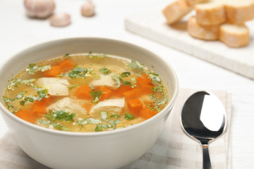 Bowl with fresh homemade chicken soup on table, closeup