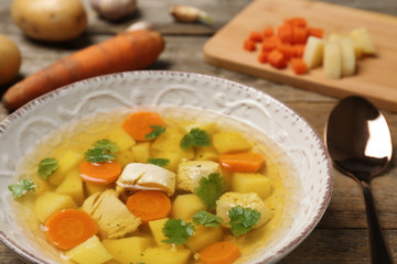 Dish with fresh homemade chicken soup on wooden table, closeup
