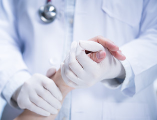 Medical doctor wearing latex gloves holding patient’s hand to give support in hospital setting