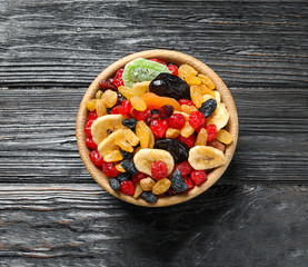 Bowl with different dried fruits on wooden background, top view. Healthy lifestyle