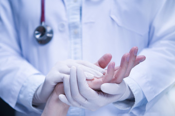 Medical doctor wearing latex gloves holding patient’s hand to give support in hospital setting