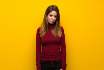 Woman with turtleneck over yellow wall with sad and depressed expression