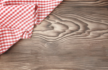 Red picnic cloth on wooden background.