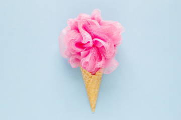 Composition of ice cream cone with pink wisp of bast on a light blue background. Bathroom cosmetic...