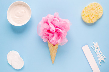 Composition of ice cream cone with pink wisp of bast on a light blue background. Bathroom cosmetic accessories. Flat Lay. Top View