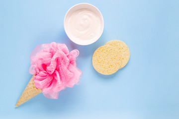 Composition of ice cream cone with pink wisp of bast on a light blue background. Bathroom cosmetic accessories. Flat Lay. Top View