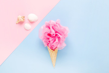 Composition of ice cream cone with pink wisp of bast on a light blue background. Bathroom cosmetic accessories. Flat Lay. Top View