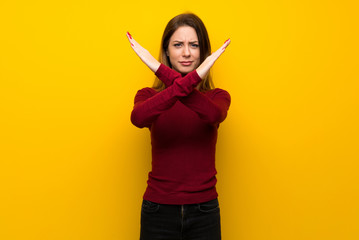 Woman with turtleneck over yellow wall making NO gesture