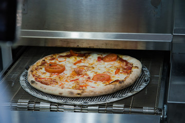 Ready-made Italian pizza on thin dough cooked in special equipment. Selective focus