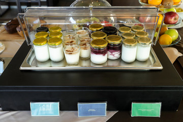 Full and low fat yoghurt, rice pudding in jars for healthy breakfast buffet table in greek hotel.
