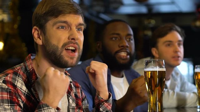 Male friends supporting sports team in pub, disappointed about ball offside