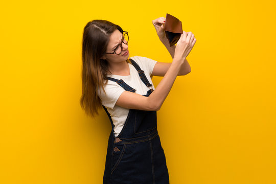 Woman over yellow wall holding a wallet