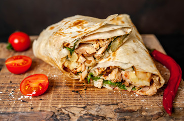 Burrito wraps with chicken and vegetables on a cutting board, against a background of concrete, Mexican shawarma