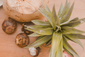 stiil life with exotic fruits mangosteen, coconut and pineapple on the wood table in tropical garden in Bali