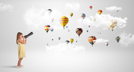 Cute girl looking to air balloons through a telescope
