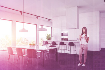 Fototapeta premium Woman in white kitchen corner with table and bar