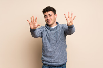 Young man over isolated wall counting nine with fingers