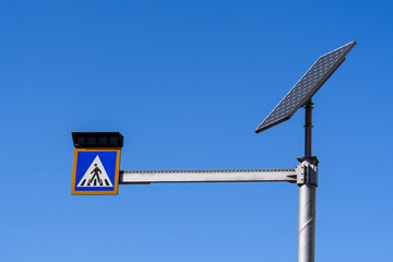 Sign of crossing of pedestrians with lights activated by a solar panel display in Bucharest, Romania, on clear blue sky