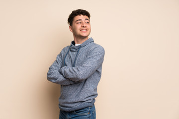 Young man over isolated wall with arms crossed and happy
