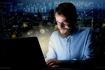 Young handsome businessman working late at night in the office with blue calculations in the background