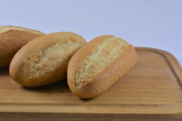 three french breads on a wooden cutting board on a white background