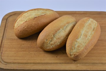 three french breads on a wooden cutting board on a white background