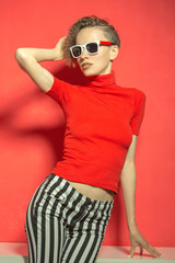 Gorgeous short-haired girl in sunglasses on red background