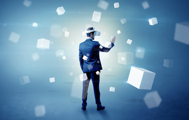 Handsome businessman with vr goggle and falling white cubes around
