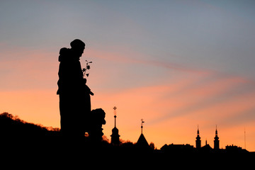 Sights of Prague, Czech Republic. Beautiful landscape silhouettes of sculptures against sky. Sunset backlit silhouettes of statues and roofs on hill background of cityscape skyline at Charles Bridge.