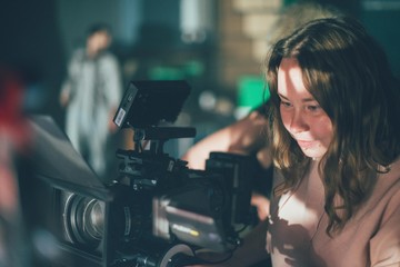 Girl cameraman behind camera on set