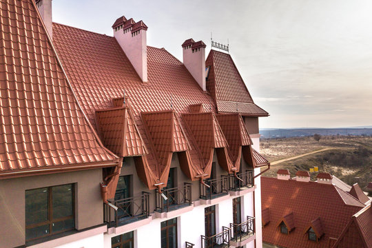 Close-up of building facade exterior with stucco wall, cast iron balcony railings, steep shingle roof and shiny windows.