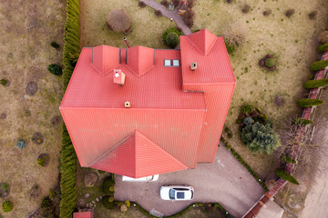 Aerial top view of new residential house cottage with shingle roof on fenced big yard on sunny day.