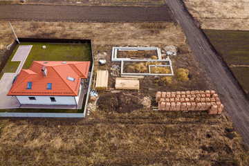 Aerial view of new house roof with attic windows and building site, foundation of future house,...