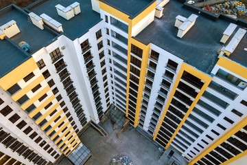 Aerial view of tall apartment building complex. Blue flat roof with chimneys, inner yard, row of windows. Drone photography.