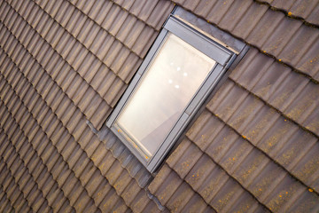Close-up of new attic plastic window installed in shingled house roof. Professionally done building and construction work, roofing and installation concept.