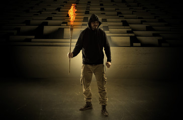 Ugly, aberrant man coming out from the labyrinth with burning flambeau on his hand
