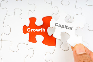Fototapeta premium Hand holding piece of jigsaw puzzle with word CAPITAL GROWTH. Selective focus