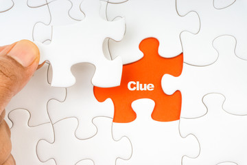 Fototapeta premium Hand holding piece of jigsaw puzzle with word CLUE. Selective focus