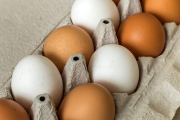 Hen eggs in open cardboard egg carton on kitchen table light copy space background. Healthy organic food and diet concept.
